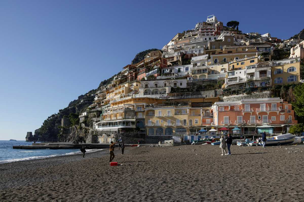 Foto panoramica di una festa tradizionale serale a Positano, con la chiesa di Santa Maria Assunta illuminata, folla festante e fuochi d’artificio sul mare
